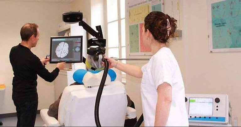 Séance de rTMS au CHU de Rennes : un patient reçoit une stimulation magnétique transcrânienne ; on aperçoit la bobine en forme de 8 positionnée sur le crâne, le système de neuronavigation avec IRM 3D du cerveau à l'écran, et la console de stimulation manipulée par l'équipe médicale